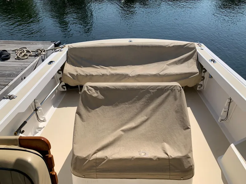 Slide: The Image of 2004 Hunt Yachts Surfhunter 25 boat interior with beige covers, docked by calm water. - 21
