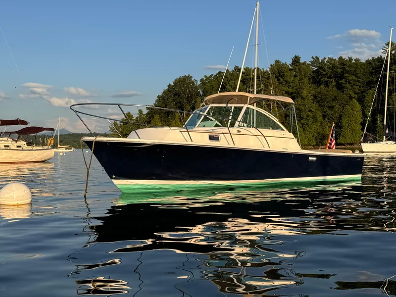 Slide: The Image of 2004 Hunt Yachts Surfhunter 25 on calm water, surrounded by trees and other boats. - 26