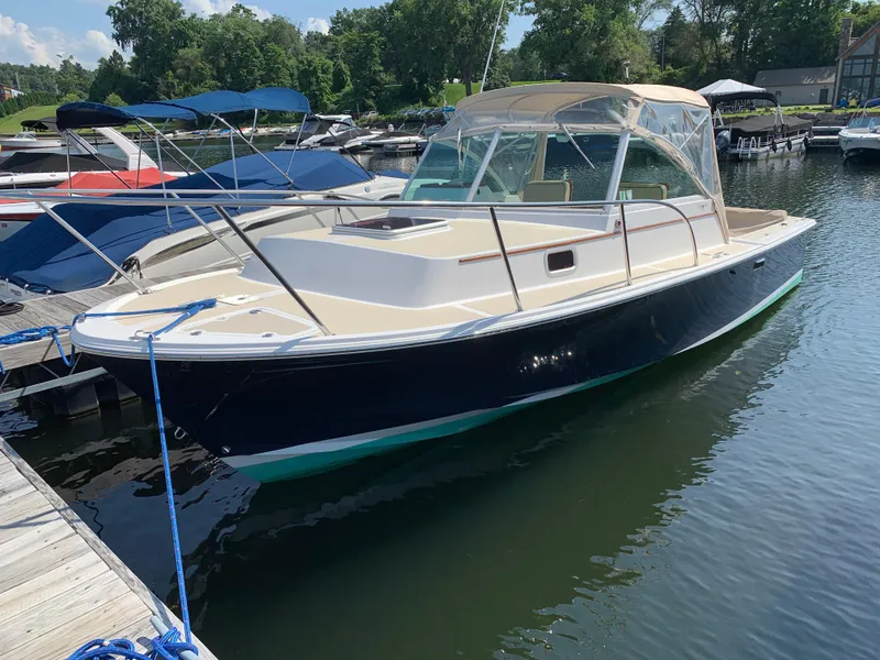 Slide: The Image of 2004 Hunt Yachts Surfhunter 25 docked in a marina, featuring a sleek design and canopy. - 4