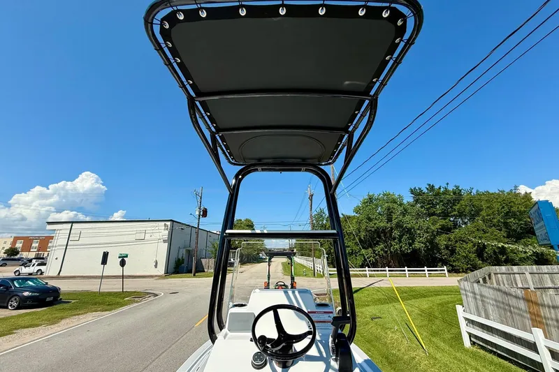Slide: The Image of 2026 Shallow Sport 24 Modified V boat with T-top, steering wheel, and clear blue sky. - 11