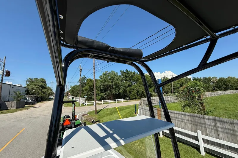 Slide: The Image of 2026 Shallow Sport 24 Modified V boat with T-top, parked near a road and greenery. - 18