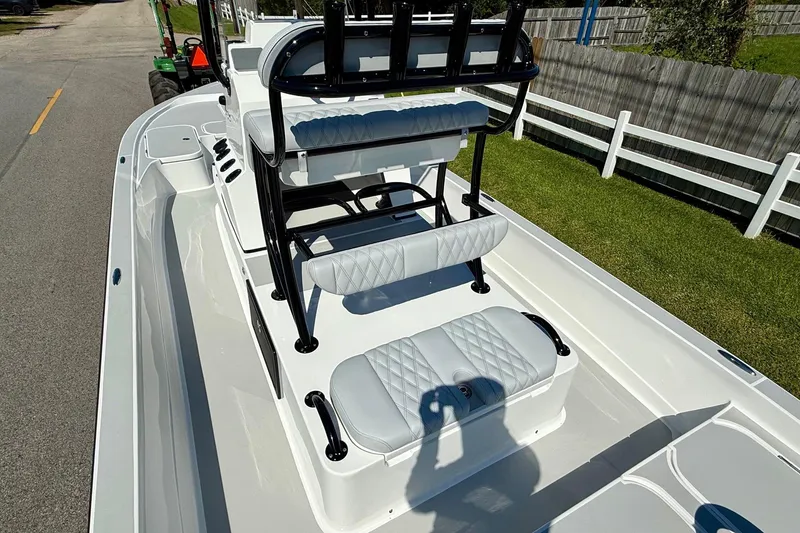 Slide: The Image of 2026 Shallow Sport 24 Modified V boat interior with seating and console, parked on a road. - 8