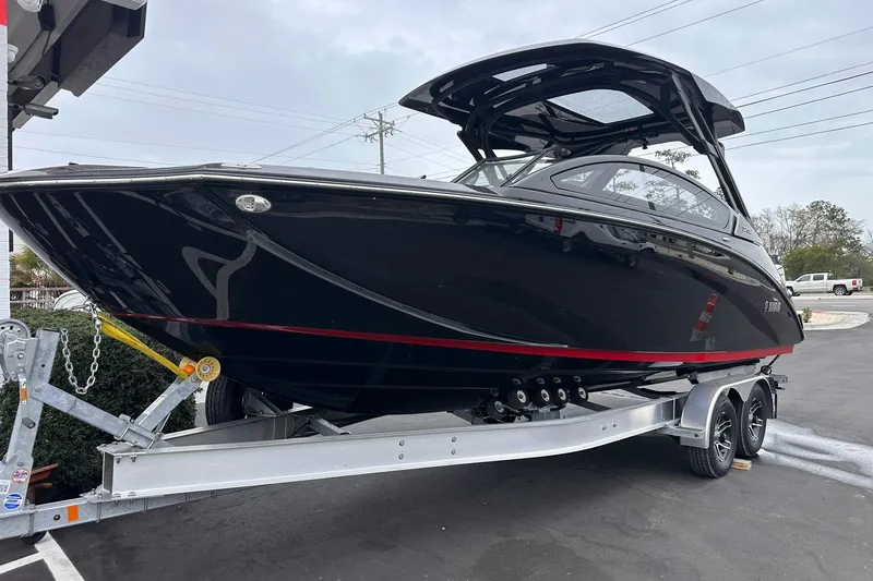Slide: The Image of 2025 Yamaha Boats 275SD on trailer, sleek black design with red accents. - 12