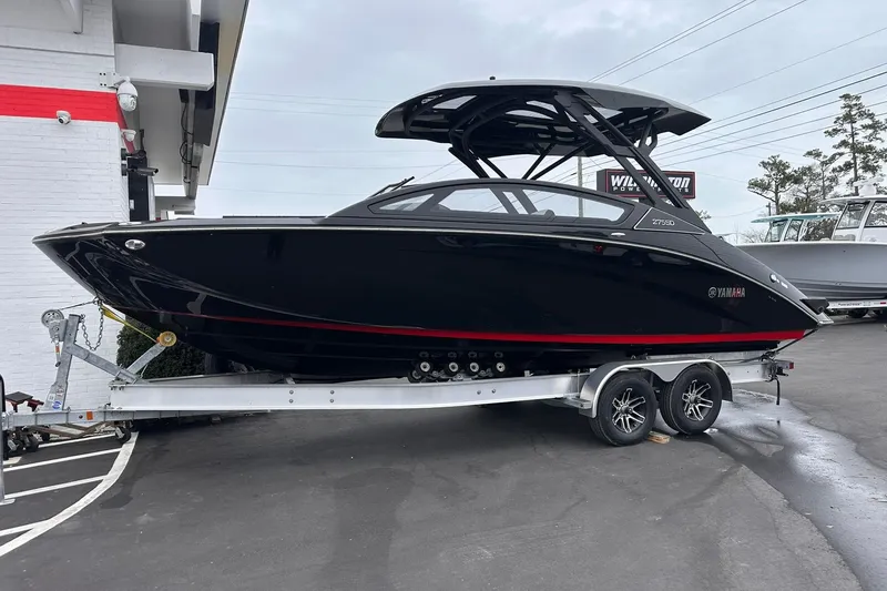 Slide: The Image of 2025 Yamaha Boats 275SD in black on trailer, parked outdoors. - 13