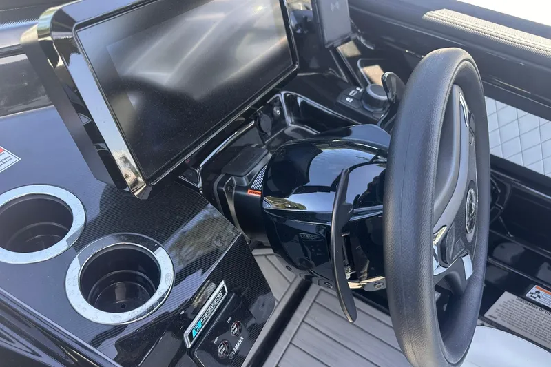 Slide: The Image of Steering console of 2025 Yamaha Boats 275SD with touchscreen and cup holders. - 28