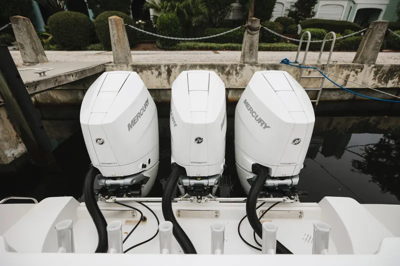 Slide: The Image of Triple Mercury outboard engines on a 2008 Everglades 350LX boat docked by the water. - 26