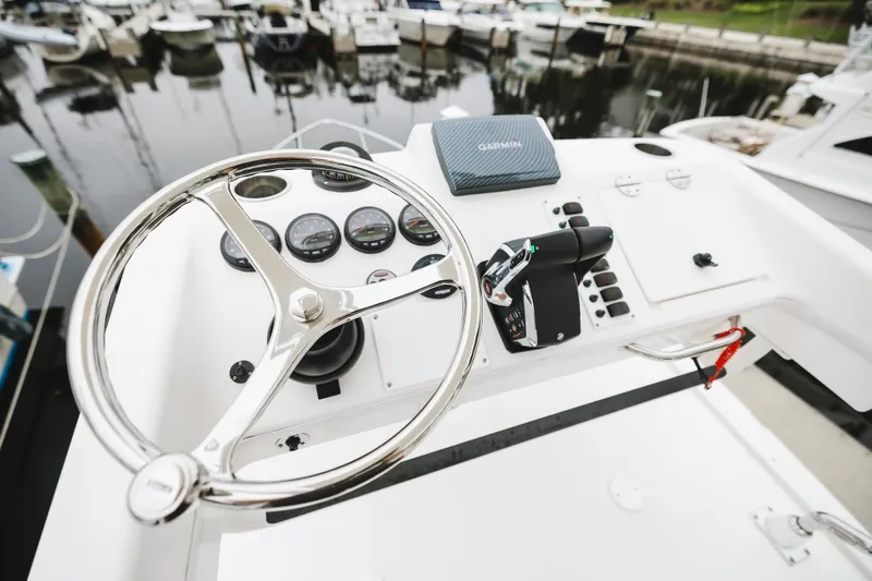 Slide: The Image of Steering wheel and controls of a 2008 Everglades 350LX boat at a marina. - 43