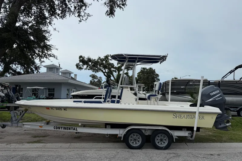 The Image of 2006 ShearWater Z2200 boat on trailer with Yamaha outboard motor, parked near a house. - 0