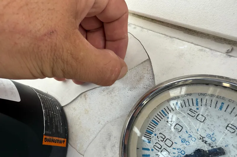 Slide: The Image of Hand inspecting cracked surface near gauge on 2006 ShearWater Z2200 boat. - 32