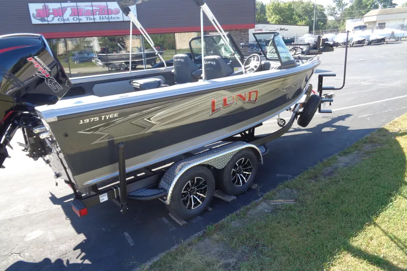 Slide: The Image of 2026 Lund 1975 Tyee boat on trailer, parked outside a marine dealership. - 28