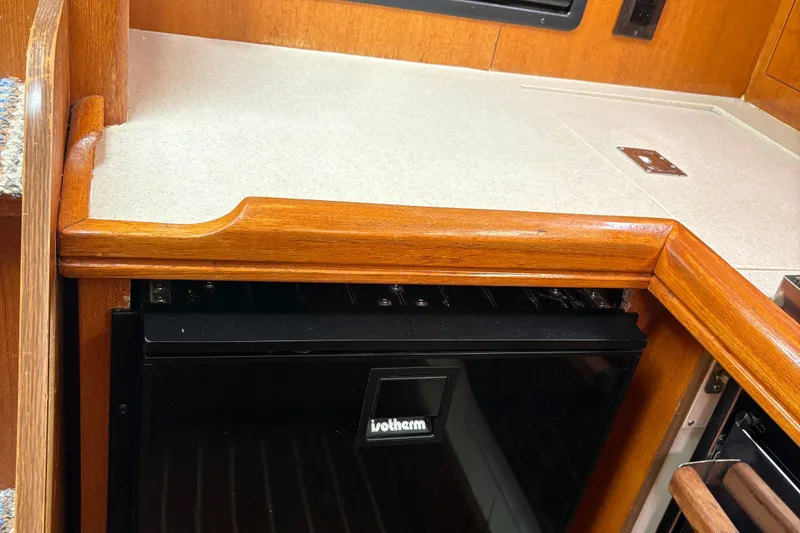 Slide: The Image of 2006 Hunter 33 yacht interior with wooden cabinetry and compact fridge. - 16
