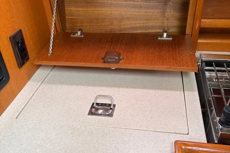 Slide: The Image of 2006 Hunter 33 yacht interior, featuring a wooden cabinet and countertop with a metal latch. - 17