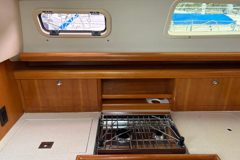 Slide: The Image of Interior of a 2006 Hunter 33 sailboat featuring a compact wooden kitchen with stove. - 19