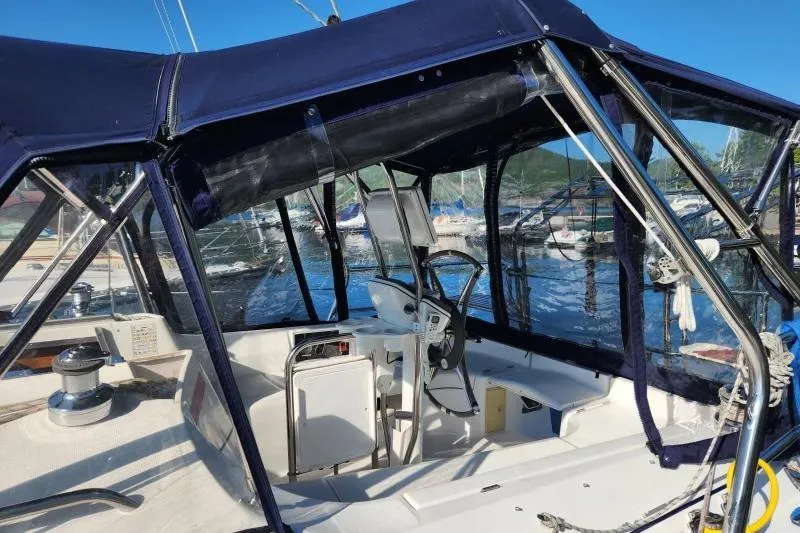 Slide: The Image of 2006 Hunter 33 sailboat cockpit with blue canopy and steering wheel, docked at marina. - 2