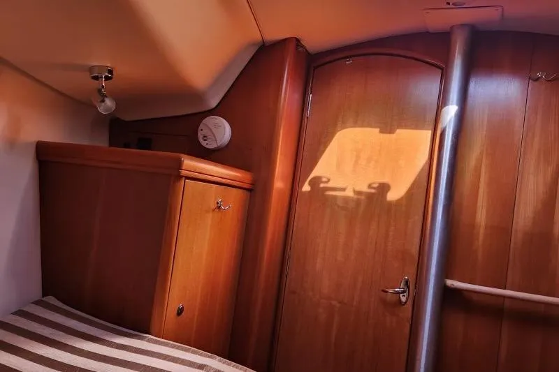 Slide: The Image of Interior of a 2006 Hunter 33 sailboat cabin with wooden finish and striped bedding. - 29