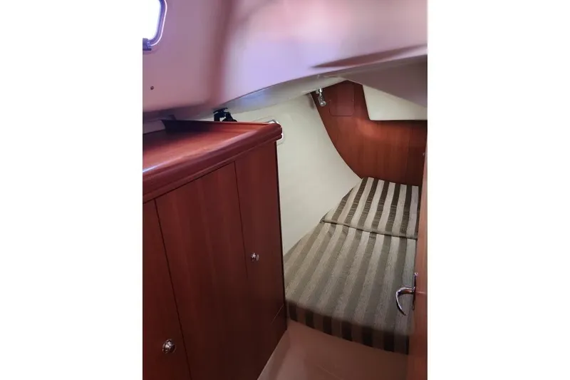 Slide: The Image of 2006 Hunter 33 yacht interior cabin with striped bedding and wooden cabinetry. - 34
