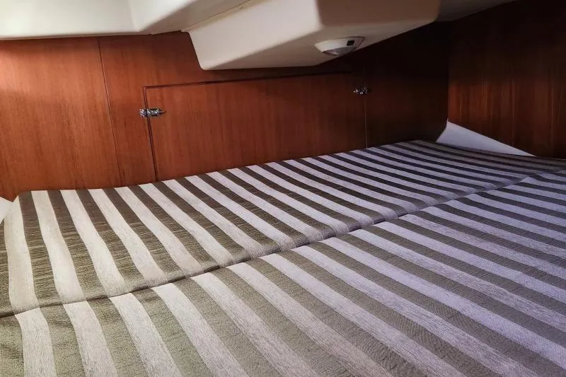 Slide: The Image of Interior cabin of 2006 Hunter 33 sailboat with striped bedding and wooden paneling. - 36