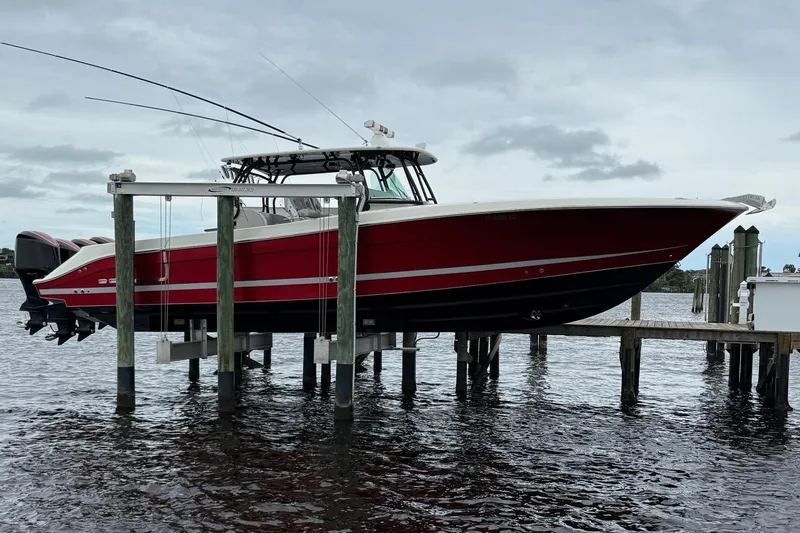 The Image of 2013 Hydra-Sports 42 boat on lift, red hull, docked by the water. - 0