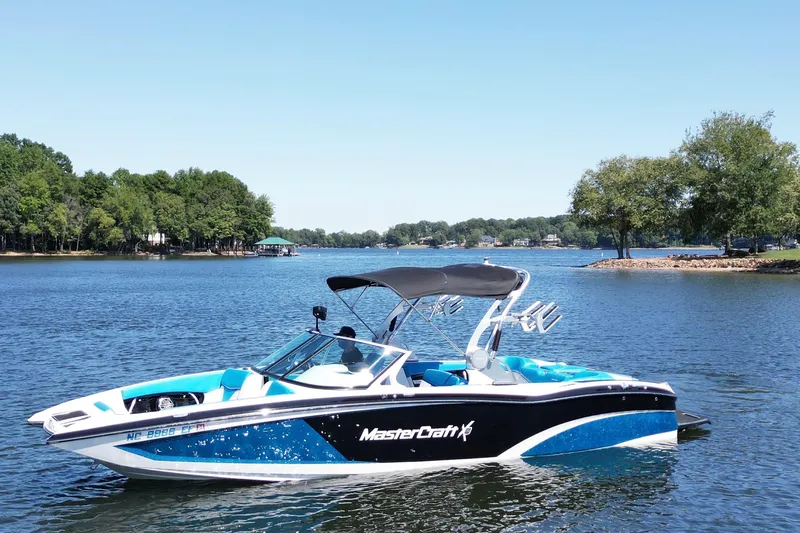 Slide: The Image of 2017 MasterCraft X26 boat on a serene lake with lush green trees. - 0