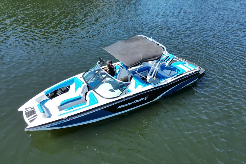 Slide: The Image of 2017 MasterCraft X26 boat on water, featuring blue and white design with canopy. - 10