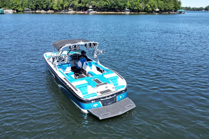 Slide: The Image of 2017 MasterCraft X26 boat on a serene lake with lush green shoreline. - 12