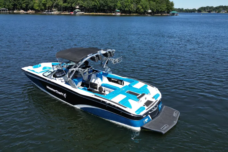 Slide: The Image of 2017 MasterCraft X26 boat on a serene lake with lush green shoreline. - 4