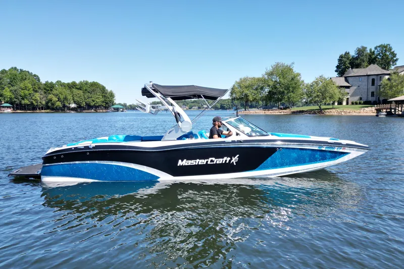 Slide: The Image of 2017 MasterCraft X26 boat on a lake with trees and houses in the background. - 6