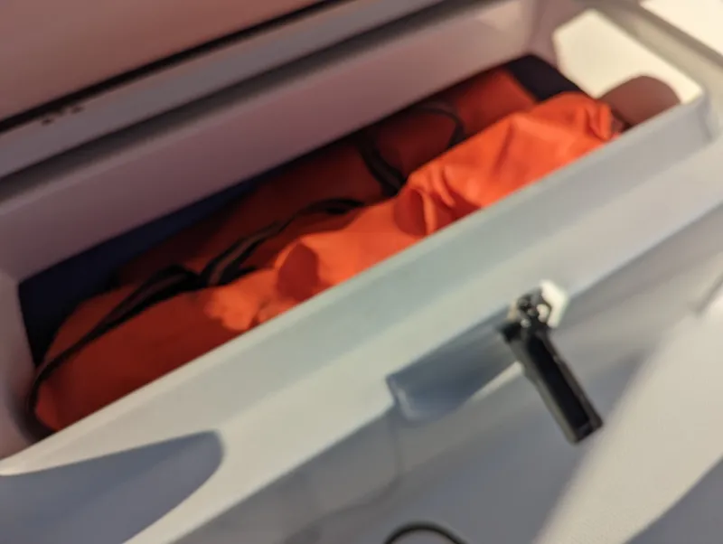 Slide: The Image of Storage compartment with orange life jacket in a 2017 Mako 204 Center Console boat. - 10