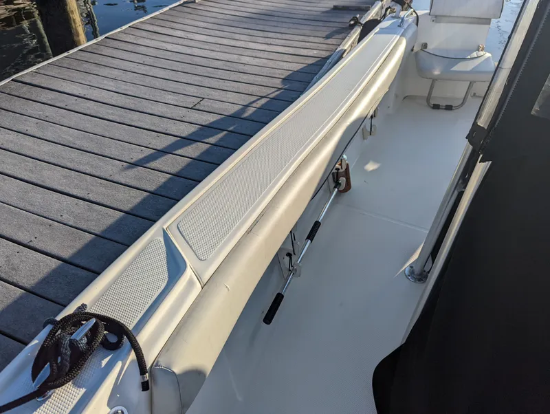 Slide: The Image of 2017 Mako 204 Center Console boat docked, showing interior seating and deck details. - 13