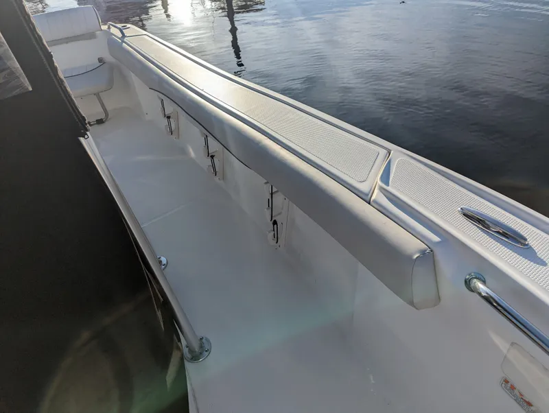 Slide: The Image of 2017 Mako 204 Center Console boat interior with seating and storage, docked by the water. - 14