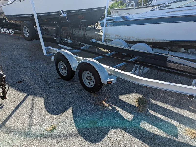 Slide: The Image of Boat trailer with dual axles parked on cracked pavement, near a Mako 204 Center Console. - 5