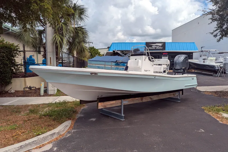 Slide: The Image of 2026 BlackJack 224 boat displayed outdoors on a stand, under a cloudy sky. - 1