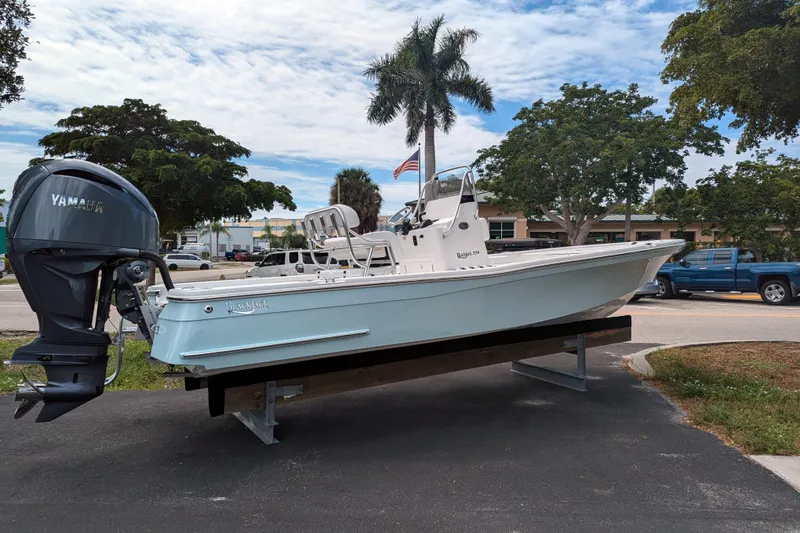 Slide: The Image of 2026 BlackJack 224 boat on trailer, displayed outdoors with trees and building in background. - 3