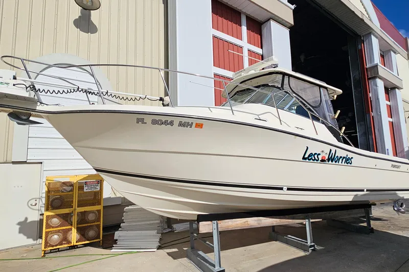 The Image of 2004 Pursuit 3070 Express boat named "Less Worries" on a stand outside a building. - 0