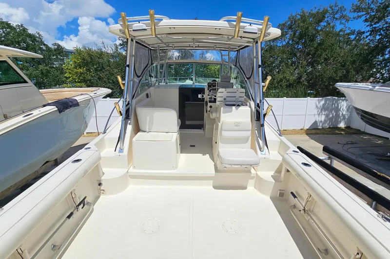 Slide: The Image of 2004 Pursuit 3070 Express boat interior with seating and helm, docked outdoors. - 14