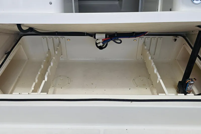 Slide: The Image of 2004 Pursuit 3070 Express boat storage compartment with organized dividers and wiring. - 20