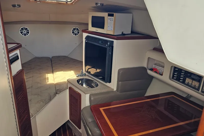 Slide: The Image of 2004 Pursuit 3070 Express cabin interior with bed, kitchenette, and seating area. - 27