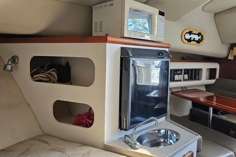 Slide: The Image of 2004 Pursuit 3070 Express cabin interior with microwave, sink, and storage compartments. - 29