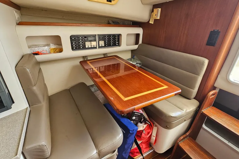 Slide: The Image of 2004 Pursuit 3070 Express cabin with wooden table, cushioned seating, and control panel. - 30