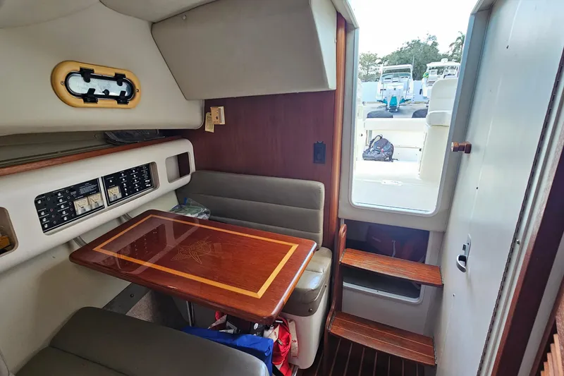 Slide: The Image of 2004 Pursuit 3070 Express cabin interior with seating and wooden table. - 31