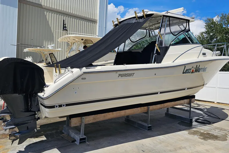 Slide: The Image of 2004 Pursuit 3070 Express boat on dry dock, covered, with clear skies. - 34