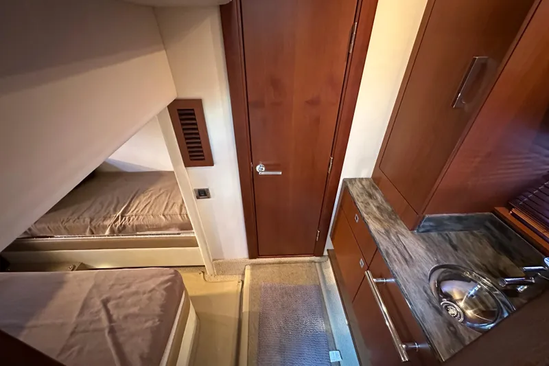 Slide: The Image of 2012 Sea Ray 470 Sundancer cabin interior with wood finish and compact sink area. - 26