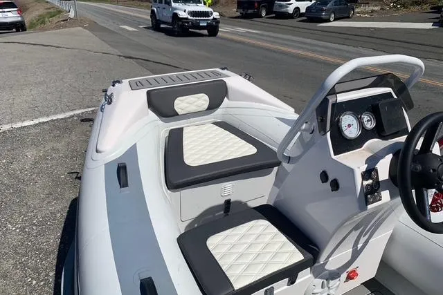 Slide: The Image of 2023 Highfield Sport 330 boat with white and black seating, parked near a road. - 10