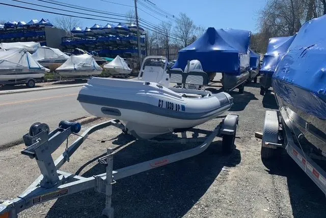 Slide: The Image of 2023 Highfield Sport 330 boat on trailer, parked outdoors with other covered boats. - 6