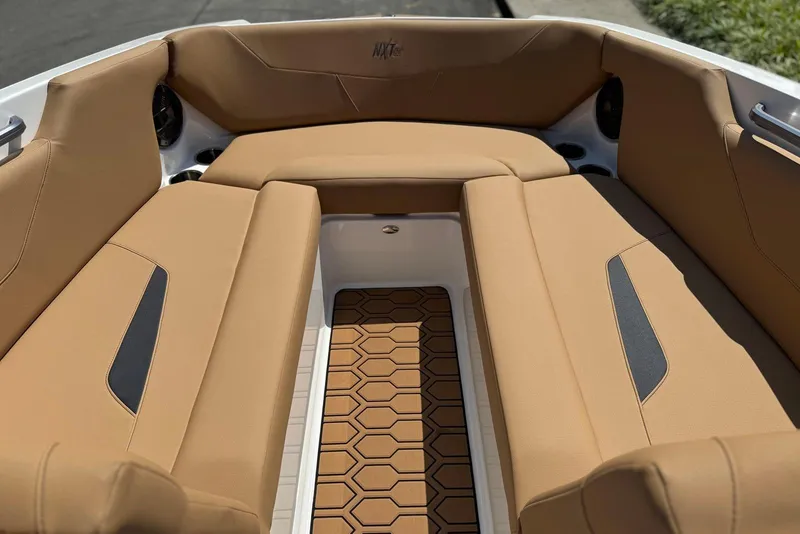 Slide: The Image of 2021 MasterCraft NXT24 boat on trailer, parked outdoors with trees in background. - 14