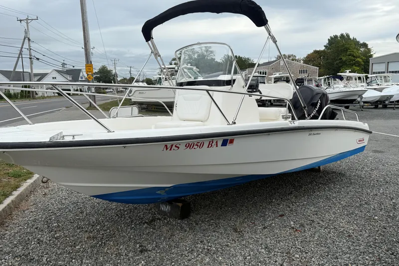 Slide: The Image of 2007 Boston Whaler 200 Dauntless boat on gravel lot, with blue hull and canopy. - 0