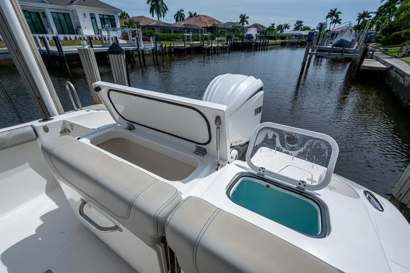 Slide: The Image of 2022 Pursuit DC 246 Dual Console boat with open storage compartments by a dock. - 14