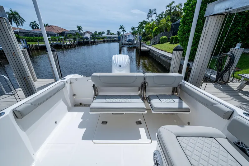 Slide: The Image of 2022 Pursuit DC 246 Dual Console boat interior with seating, docked by a scenic canal. - 15