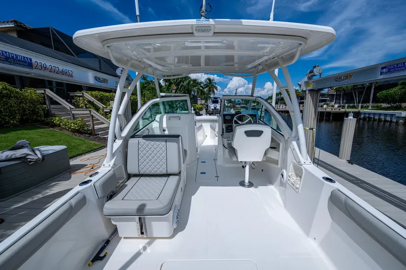 Slide: The Image of 2022 Pursuit DC 246 Dual Console boat interior at marina, featuring seating and helm. - 18