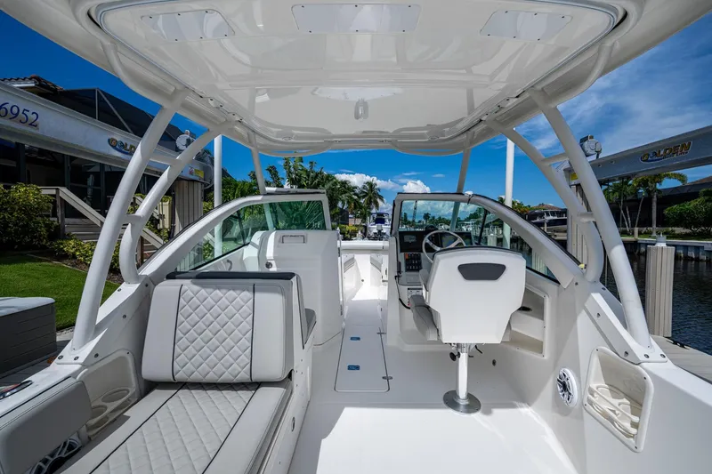 Slide: The Image of 2022 Pursuit DC 246 Dual Console boat interior with seating and helm, docked by a marina. - 19